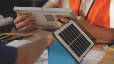 İki mimar planları analiz ediyor ve ofis ortamındaki bir inşaat projesi hakkında detaylı bir tartışmaya girişiyorlar.