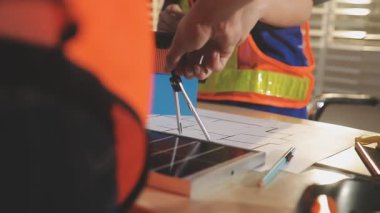 İki mimar planları analiz ediyor ve ofis ortamındaki bir inşaat projesi hakkında detaylı bir tartışmaya girişiyorlar.