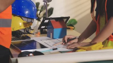 İki mimar planları analiz ediyor ve ofis ortamındaki bir inşaat projesi hakkında detaylı bir tartışmaya girişiyorlar.