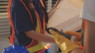 İki mimar planları analiz ediyor ve ofis ortamındaki bir inşaat projesi hakkında detaylı bir tartışmaya girişiyorlar.