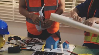 İki mimar planları analiz ediyor ve ofis ortamındaki bir inşaat projesi hakkında detaylı bir tartışmaya girişiyorlar.