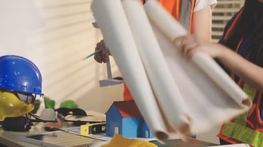 İki mimar planları analiz ediyor ve ofis ortamındaki bir inşaat projesi hakkında detaylı bir tartışmaya girişiyorlar.