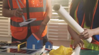 İki mimar planları analiz ediyor ve ofis ortamındaki bir inşaat projesi hakkında detaylı bir tartışmaya girişiyorlar.