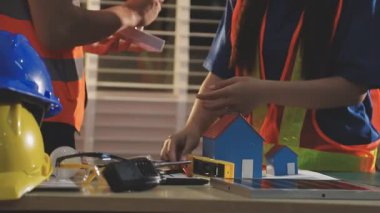 İki mimar planları analiz ediyor ve ofis ortamındaki bir inşaat projesi hakkında detaylı bir tartışmaya girişiyorlar.