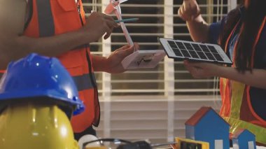 İki mimar planları analiz ediyor ve ofis ortamındaki bir inşaat projesi hakkında detaylı bir tartışmaya girişiyorlar.