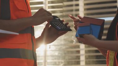 İki mimar planları analiz ediyor ve ofis ortamındaki bir inşaat projesi hakkında detaylı bir tartışmaya girişiyorlar.