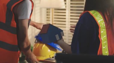 İki mimar planları analiz ediyor ve ofis ortamındaki bir inşaat projesi hakkında detaylı bir tartışmaya girişiyorlar.