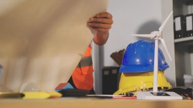 İki mimar planları analiz ediyor ve ofis ortamındaki bir inşaat projesi hakkında detaylı bir tartışmaya girişiyorlar.