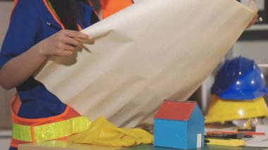 İki mimar planları analiz ediyor ve ofis ortamındaki bir inşaat projesi hakkında detaylı bir tartışmaya girişiyorlar.