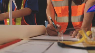 İki mimar planları analiz ediyor ve ofis ortamındaki bir inşaat projesi hakkında detaylı bir tartışmaya girişiyorlar.