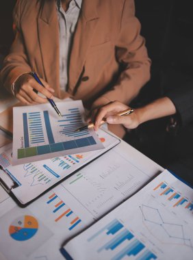 İki iş adamı toplantı odasında proje stratejisi hakkında konuşuyor. İş adamı, mali veri raporu hakkında sohbet ve tavsiyelerde bulunurken, modern işyerindeki iş arkadaşıyla proje planlamasını tartıştı.