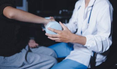 Evde dambıl kullanarak fizyoterapist eğitimi alan yaşlı bir kadın. Terapist, huzurevi egzersizlerinde yaşlı kadına yardım ediyor. Yaşlı bir hasta kollarını uzatmış halterler kullanıyor..