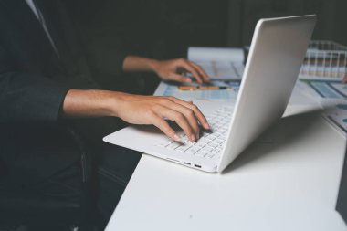 İki iş adamı toplantı odasında proje stratejisi hakkında konuşuyor. İş adamı, mali veri raporu hakkında sohbet ve tavsiyelerde bulunurken, modern işyerindeki iş arkadaşıyla proje planlamasını tartıştı.