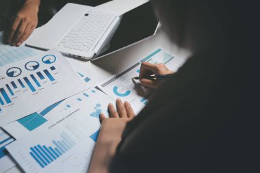 İki iş adamı toplantı odasında proje stratejisi hakkında konuşuyor. İş adamı, mali veri raporu hakkında sohbet ve tavsiyelerde bulunurken, modern işyerindeki iş arkadaşıyla proje planlamasını tartıştı.