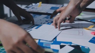 Uxui tasarımcılarından oluşan bir ekip bilgisayar ekranını işaret ederek ofiste yeni mobil uygulama tasarımını tartışıyor.