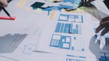 Uxui tasarımcılarından oluşan bir ekip bilgisayar ekranını işaret ederek ofiste yeni mobil uygulama tasarımını tartışıyor.