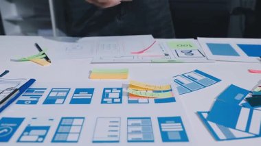 Uxui tasarımcılarından oluşan bir ekip bilgisayar ekranını işaret ederek ofiste yeni mobil uygulama tasarımını tartışıyor.