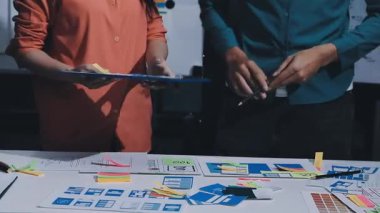 Uxui tasarımcılarından oluşan bir ekip bilgisayar ekranını işaret ederek ofiste yeni mobil uygulama tasarımını tartışıyor.