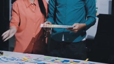 Uxui tasarımcılarından oluşan bir ekip bilgisayar ekranını işaret ederek ofiste yeni mobil uygulama tasarımını tartışıyor.