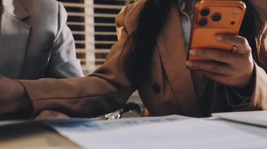 Karmaşık ofis masasında hesap makinesiyle basılı mali raporları inceleyen muhasebeci, denetim ve kurumsal finans işleri için yumuşak pencere ışığı altında yapışkan notlar tutuyor.