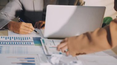 Karmaşık ofis masasında hesap makinesiyle basılı mali raporları inceleyen muhasebeci, denetim ve kurumsal finans işleri için yumuşak pencere ışığı altında yapışkan notlar tutuyor.