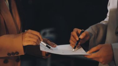 Karmaşık ofis masasında hesap makinesiyle basılı mali raporları inceleyen muhasebeci, denetim ve kurumsal finans işleri için yumuşak pencere ışığı altında yapışkan notlar tutuyor.