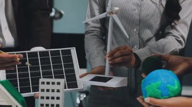 Genç Asyalı işadamı güneş panelinin modelini ofisinde tutuyor..