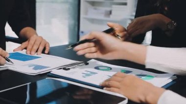 Bir grup iş ortağı ofiste mali belgeleri ve fikirleri tartışıyor.