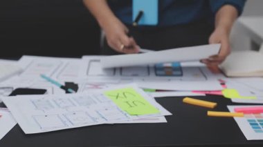 UXUI tasarımı üzerinde çalışan profesyonel bir kadın, bir arama sırasında mobil uygulama için kablolar ve modeller yaratıyor