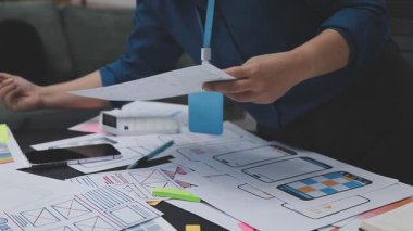 UXUI tasarımı üzerinde çalışan profesyonel bir kadın, bir arama sırasında mobil uygulama için kablolar ve modeller yaratıyor