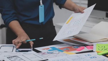 UXUI tasarımı üzerinde çalışan profesyonel bir kadın, bir arama sırasında mobil uygulama için kablolar ve modeller yaratıyor