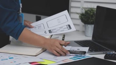 UXUI tasarımı üzerinde çalışan profesyonel bir kadın, bir arama sırasında mobil uygulama için kablolar ve modeller yaratıyor