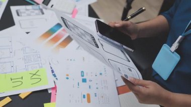 UXUI tasarımı üzerinde çalışan profesyonel bir kadın, bir arama sırasında mobil uygulama için kablolar ve modeller yaratıyor