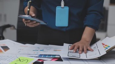 UXUI tasarımı üzerinde çalışan profesyonel bir kadın, bir arama sırasında mobil uygulama için kablolar ve modeller yaratıyor