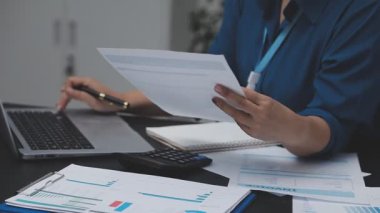 Muhasebe şirketi kazançlı nakit akışı için finansman ve vergilendirme planlaması, ofiste çalışan denetçi ve muhasebeci ekibi, mali verileri ve muhasebe kayıtlarını hesap makinesiyle analiz eder.