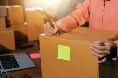 Girişim KOBİ küçük işletme girişimcisi önlük giyen Asyalı kadın dizüstü bilgisayar ve kutu kullanarak çevrimiçi müşterilere, çevrimiçi sme iş fikirlerine satış hazırlamak için siparişleri alır ve gözden geçirir.