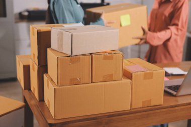 Girişim KOBİ küçük işletme girişimcisi önlük giyen Asyalı kadın dizüstü bilgisayar ve kutu kullanarak çevrimiçi müşterilere, çevrimiçi sme iş fikirlerine satış hazırlamak için siparişleri alır ve gözden geçirir.