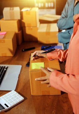 Girişim KOBİ küçük işletme girişimcisi önlük giyen Asyalı kadın dizüstü bilgisayar ve kutu kullanarak çevrimiçi müşterilere, çevrimiçi sme iş fikirlerine satış hazırlamak için siparişleri alır ve gözden geçirir.