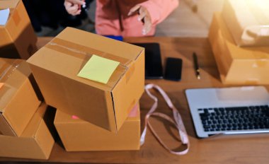 Girişim KOBİ küçük işletme girişimcisi önlük giyen Asyalı kadın dizüstü bilgisayar ve kutu kullanarak çevrimiçi müşterilere, çevrimiçi sme iş fikirlerine satış hazırlamak için siparişleri alır ve gözden geçirir.