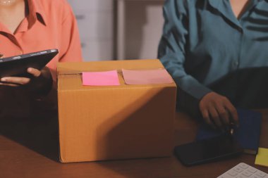 Girişim KOBİ küçük işletme girişimcisi önlük giyen Asyalı kadın dizüstü bilgisayar ve kutu kullanarak çevrimiçi müşterilere, çevrimiçi sme iş fikirlerine satış hazırlamak için siparişleri alır ve gözden geçirir.