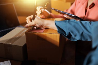 Girişim KOBİ küçük işletme girişimcisi önlük giyen Asyalı kadın dizüstü bilgisayar ve kutu kullanarak çevrimiçi müşterilere, çevrimiçi sme iş fikirlerine satış hazırlamak için siparişleri alır ve gözden geçirir.