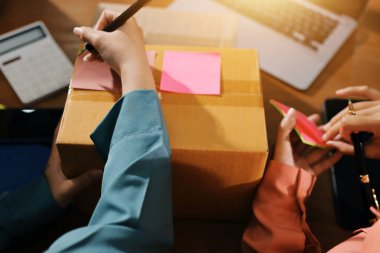 Girişim KOBİ küçük işletme girişimcisi önlük giyen Asyalı kadın dizüstü bilgisayar ve kutu kullanarak çevrimiçi müşterilere, çevrimiçi sme iş fikirlerine satış hazırlamak için siparişleri alır ve gözden geçirir.