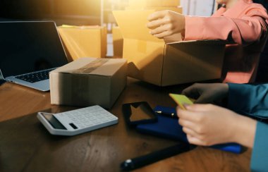 Girişim KOBİ küçük işletme girişimcisi önlük giyen Asyalı kadın dizüstü bilgisayar ve kutu kullanarak çevrimiçi müşterilere, çevrimiçi sme iş fikirlerine satış hazırlamak için siparişleri alır ve gözden geçirir.