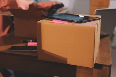 Girişim KOBİ küçük işletme girişimcisi önlük giyen Asyalı kadın dizüstü bilgisayar ve kutu kullanarak çevrimiçi müşterilere, çevrimiçi sme iş fikirlerine satış hazırlamak için siparişleri alır ve gözden geçirir.