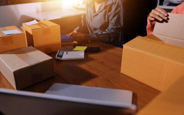 Girişim KOBİ küçük işletme girişimcisi önlük giyen Asyalı kadın dizüstü bilgisayar ve kutu kullanarak çevrimiçi müşterilere, çevrimiçi sme iş fikirlerine satış hazırlamak için siparişleri alır ve gözden geçirir.