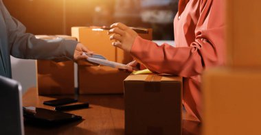 Girişim KOBİ küçük işletme girişimcisi önlük giyen Asyalı kadın dizüstü bilgisayar ve kutu kullanarak çevrimiçi müşterilere, çevrimiçi sme iş fikirlerine satış hazırlamak için siparişleri alır ve gözden geçirir.