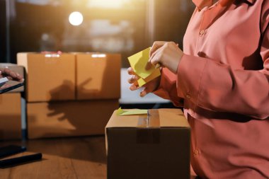 Girişim KOBİ küçük işletme girişimcisi önlük giyen Asyalı kadın dizüstü bilgisayar ve kutu kullanarak çevrimiçi müşterilere, çevrimiçi sme iş fikirlerine satış hazırlamak için siparişleri alır ve gözden geçirir.