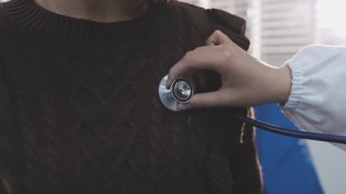 Yaşlı hastaların hayati organlarını incelemek için steteskop kullanan sevimli genç Latin doktor. Çekici İspanyol doktor, beyaz yaşlı bir kadının kalbini ve ciğerlerini kontrol etmek için tıbbi bir alet kullanıyor.