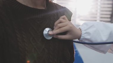 Yaşlı hastaların hayati organlarını incelemek için steteskop kullanan sevimli genç Latin doktor. Çekici İspanyol doktor, beyaz yaşlı bir kadının kalbini ve ciğerlerini kontrol etmek için tıbbi bir alet kullanıyor.