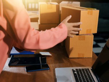 Girişim KOBİ küçük işletme girişimcisi önlük giyen Asyalı kadın dizüstü bilgisayar ve kutu kullanarak çevrimiçi müşterilere, çevrimiçi sme iş fikirlerine satış hazırlamak için siparişleri alır ve gözden geçirir.